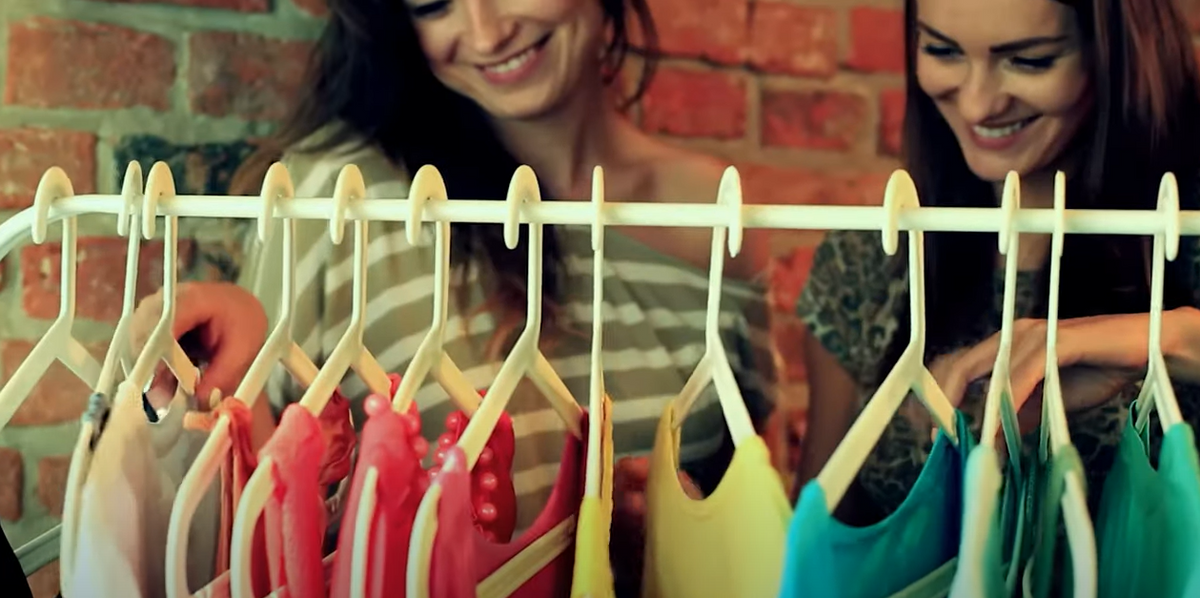 two women choosing colorful clothes on a rack